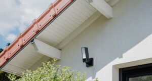 Netatmo Videocamera Esterna ORIGINAL: sicurezza 3-in-1 con registrazione locale e AI integrata Netatmo Videocamera Esterna ORIGINAL installata all’esterno con faretto LED acceso e sistema di sicurezza integrato